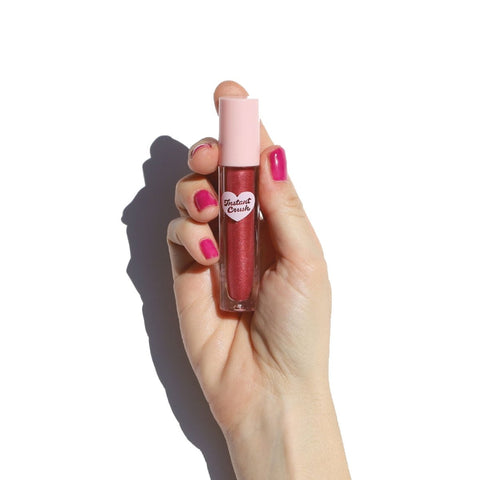 Hand with pink nail polish holding lip gloss - Instant Crush - Caught Up - Half Caked